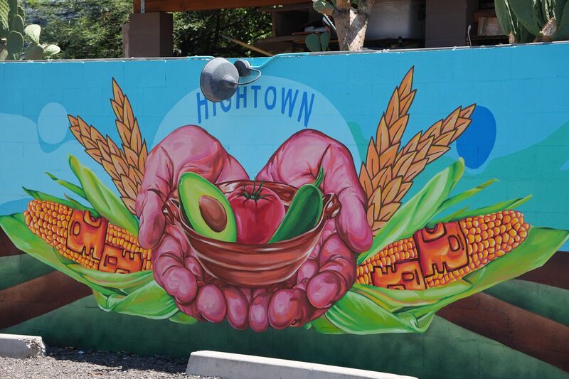 Community mural of two hands holding a bowl with an avocado, tomato and chile