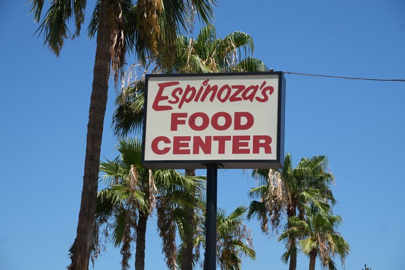 The Espinoza's Food Center sign standing against palm trees