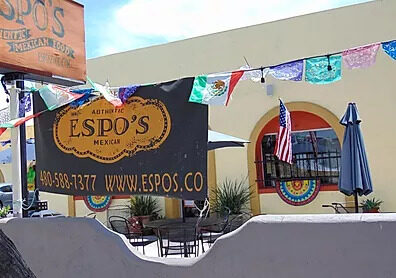 Patio tables under umbrellas beside the Espo's banner