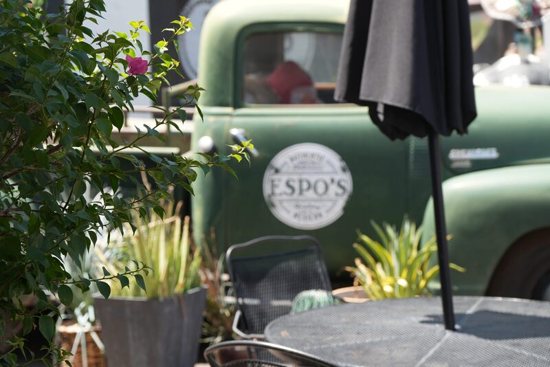 Patio tables with bougainvillea and the green Espo's truck behind them